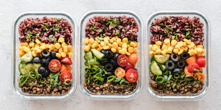 Trois contenants en verre remplis de riz complet, pois chiches, lentilles et légumes frais