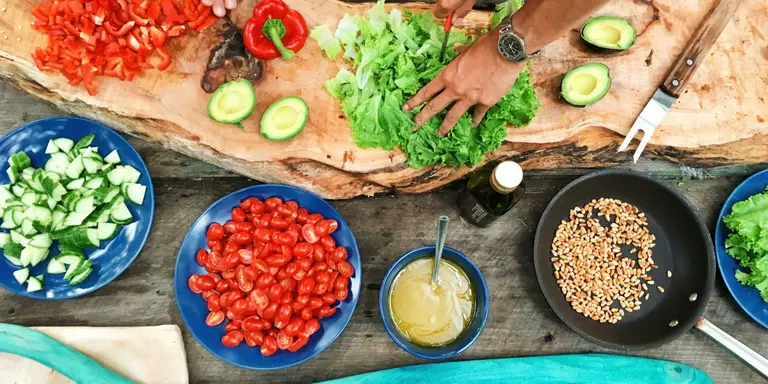 Préparation de légumes frais sur une planche en bois : poivrons, tomates cerises et salade