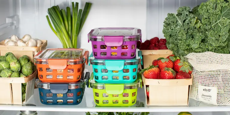 Contenants hermétiques colorés empilés dans un réfrigérateur avec des légumes et fruits frais