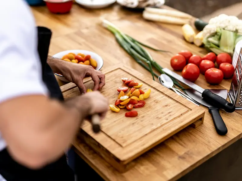 Préparation de légumes frais découpés sur une planche en bois lors d'une séance de batch cooking à Annecy